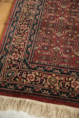 Indian Bijar rug detail: cochineal red field, Herati mahi-mahi, and navy floral border.