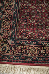 Ornate red and navy borders with a detailed Herati pattern and ivory fringe on a Bijar rug.
