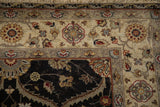 Dense wool pile on a Mogul rug's corner, with a charcoal field and contrasting sand floral border.