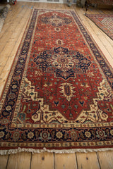 Angled full-length view of a Heriz design runner with geometric navy and brick red medallions.