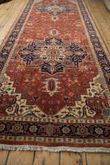 Perspective view down the length of a brick red and navy Heriz design runner with its full, even pile.