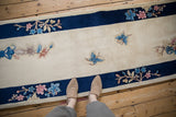 Ivory Art Deco runner, cobalt blue border, pink floral sprigs, and blue butterfly motif.