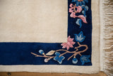 Plush Art Deco rug runner corner with cobalt blue border, pink floral spray, and ivory fringe.