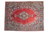 Vintage Arak carpet with a central floral medallion on a ruby red field and an intricate navy blue border.