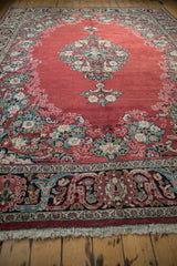 Low-angle view of a vintage Arak carpet's ruby field, floral palmette border, and medallion.
