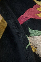 Plush dark pile of an Art Deco rug, showing raspberry, gold, and pale green details.