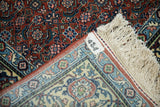The folded corner of a vintage Bulgarian rug reveals its hand-knotted back, original tag, and fringe.