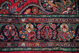 Traditional hand-knotted pile displaying cherry red, navy, and jade green floral patterns.
