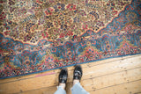 Pale indigo blue and pink blossoms in the Rococo-stylized corner of a vintage Kerman rug.