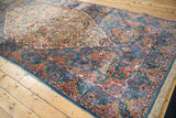 Angled view of a Kerman runner's blue scalloped corner against its ivory thousand-flower field.