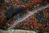 A rolled corner reveals the plush hand-knotted pile and floral motifs of a Kerman rug.