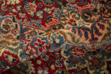 Rolled vintage Kazvin carpet showcasing intricate floral sprays in cherry red, sky blue, and ivory.
