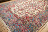 Vintage Kerman rug corner, showcasing ivory fringe and the sky blue, raspberry red cartouche border.