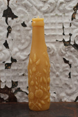 Molded antique bottle neck and exposed wick of natural beeswax candle.