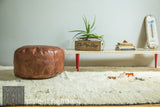 Lifestyle view of the Wooden Mod Sled Table with red mid-century legs in a room setting.