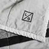 Handmade Louise Gray 'No. 9' quilt close-up, with 'L/G' logo on light gray cotton.
