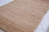 Coarse, handwoven plain weave jute rug surface with natural light and dark striations.