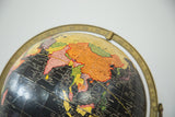Close-up of Mid Century black globe map, showing Asia's orange and pink land with black ocean.