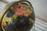 Vintage black globe map detail with colorful North America over Pacific Ocean.