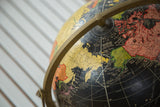 Detail of Mid Century black globe showing Arctic Ocean, yellow continents, and brass arm.