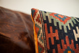 Hand-woven geometric pattern detail on antique Kilim pillow corner with vibrant tangerine velvet.