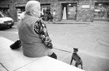 Candid black and white photograph of an older woman and dog on a Florence street.