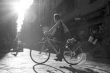 Original photograph of a biker riding through a sun-drenched Florence street.