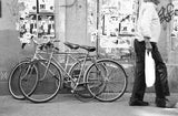 Black and white Florence street photograph featuring bicycles and a person's grocery walk.