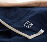 White embroidered LG logo on navy cotton Louise Gray quilt with tan binding.