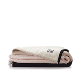 Louise Gray quilt folded, showing blush pink, khaki, and black layers with logo.