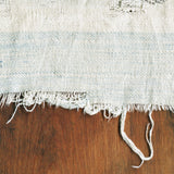 Close-up of natural woven textile, featuring subtle pale indigo bands and frayed edge.