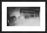Grainy black and white photograph of cows by a rustic barn.