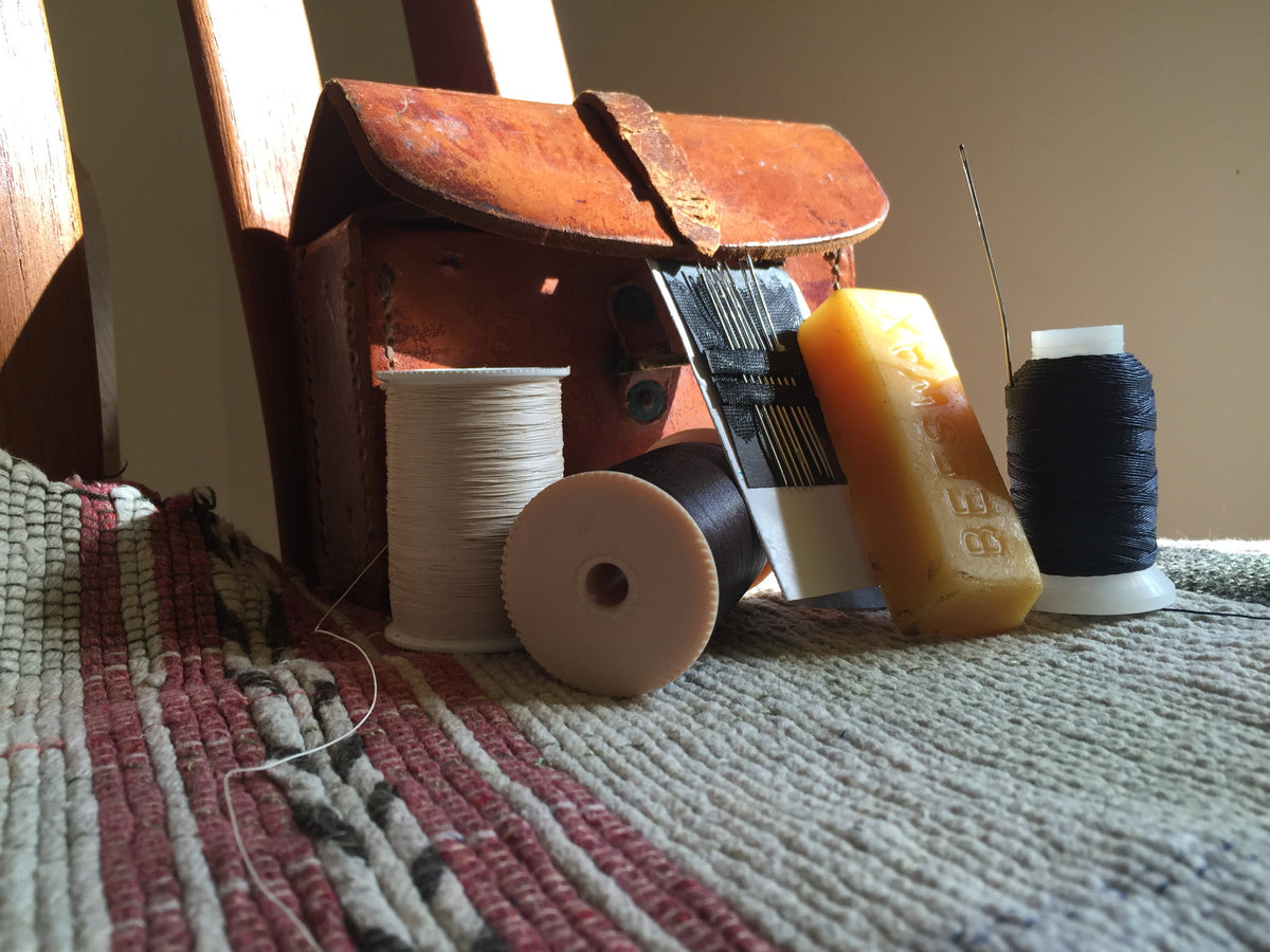 Professional tools for hand-finishing and securing carpets, including needles, thread, and wax.