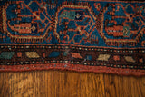 Hand-knotted wool detail of the vintage tribal rug's teal, rust, and brown pattern.