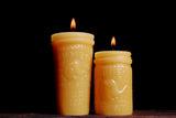 Lit yellow beeswax candles molded like 1930s Jumbo Peanut Butter jars with elephant design.