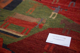 Tibetan Folk Art carpet, close-up of pictorial figures in earthy red and green.