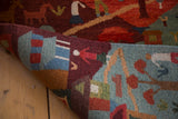 Folded view of the New Tibetan folk art rug, revealing plush pile and natural dyed pictorial scenes.