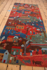 Plush pile detail of pictorial Tibetan folk art rug with villagers, animals, red, and blue.