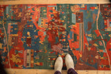 Hand-knotted Tibetan folk art rug showing plush pile with carved indigo, red, and green figures.