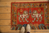 Plush hand-knotted Tibetan Fu Dog rug, ivory figure on madder red field, ornate border.