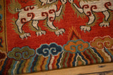 Plush, contoured pile of Tibetan Fu dog, flame, and cloud motifs in madder red, indigo, orange.