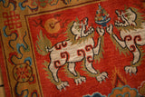 Folk art Fu dog motif with subtle carving on a plush madder root red Tibetan rug.