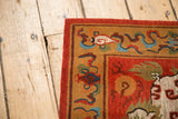 Corner detail of a Tibetan Fu Dog rug: madder red, tangerine border, indigo wavy motifs.