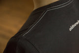 White contrast stitching along the shoulder and neckline of a men's charcoal t-shirt.