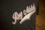 Retro Rug Addict script with a distressed texture and layered colors on a charcoal shirt.