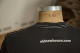 Back collar of a charcoal t-shirt showing white contrast stitch and website logo.