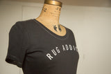 Angled view of the women's charcoal Rug Addict t-shirt, highlighting its scoop neck and contrast stitching.