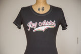 Colorful layered 'Rug Addict' graphic on a charcoal scoop neck tee with contrast stitching.