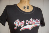 Retro 'Rug Addict' graphic and white contrast stitching on a charcoal scoop neck t-shirt.