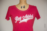 Retro 'Rug Addict' graphic with layered colors and contrast stitching on a watermelon red tee.